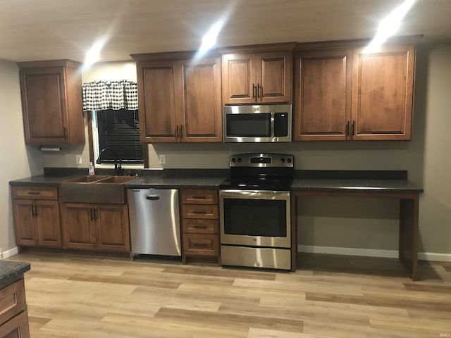 kitchen with sink, light wood-type flooring, and appliances with stainless steel finishes