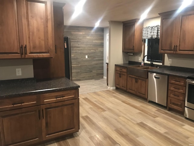 kitchen with dishwasher, wood walls, sink, light hardwood / wood-style flooring, and dark brown cabinetry