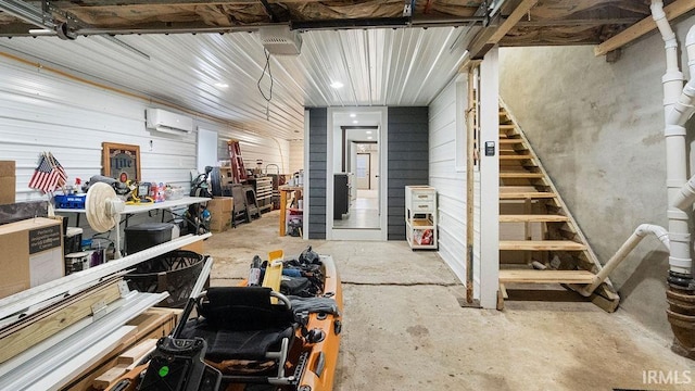 basement with a wall mounted AC, wooden walls, and a workshop area