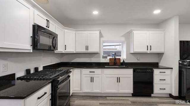 kitchen featuring sink, white cabinets, black appliances, and light hardwood / wood-style floors