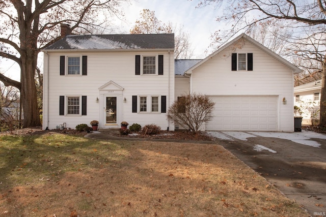 colonial home featuring a garage and a front lawn