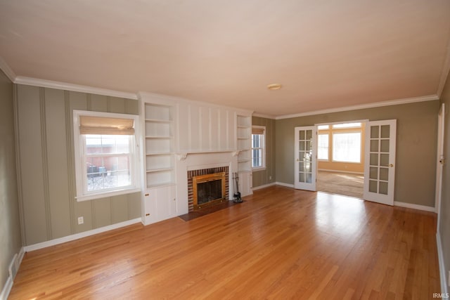 unfurnished living room featuring french doors, light hardwood / wood-style floors, ornamental molding, and a healthy amount of sunlight