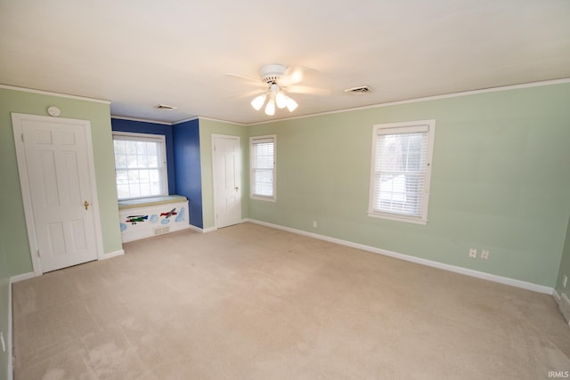 unfurnished bedroom with ceiling fan, light colored carpet, and crown molding