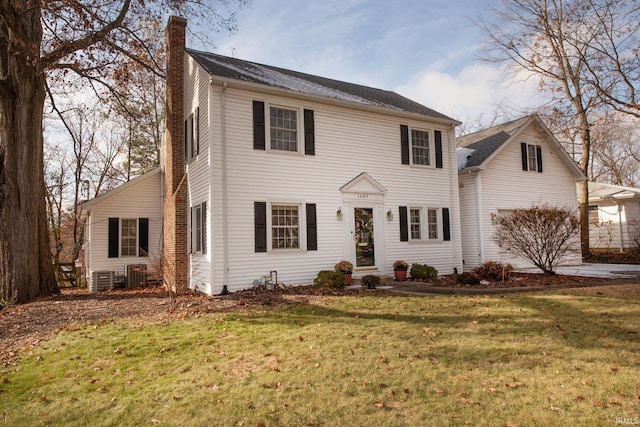 colonial house featuring central AC unit and a front lawn