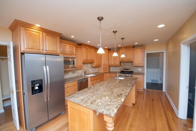 kitchen with a center island with sink, light wood-type flooring, and stainless steel appliances