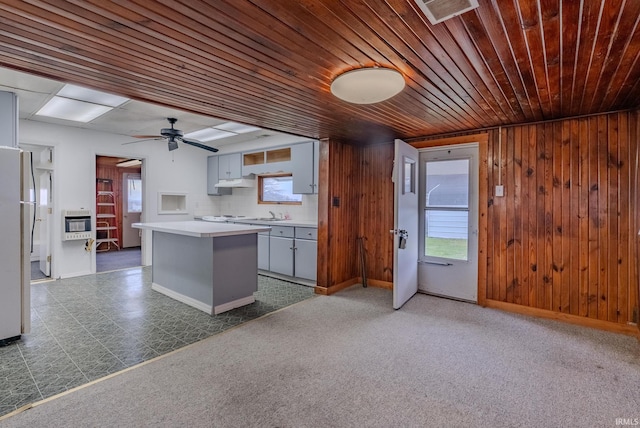 kitchen featuring a center island, wood walls, wooden ceiling, white refrigerator, and tasteful backsplash