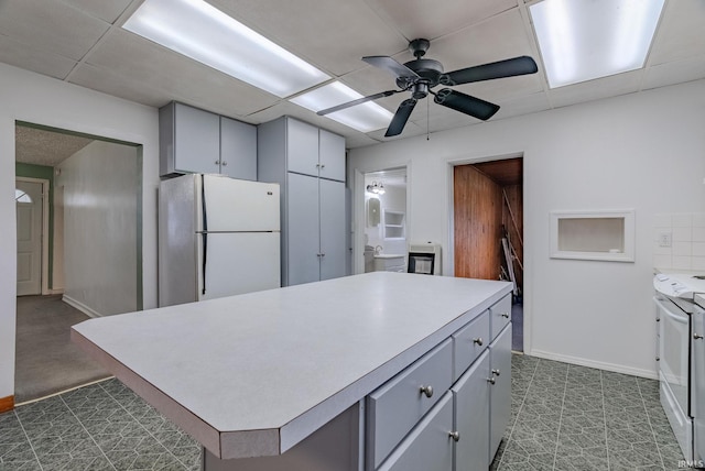 kitchen featuring gray cabinetry, ceiling fan, a kitchen island, and white appliances