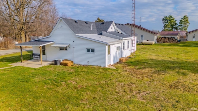 rear view of house with a lawn, cooling unit, and a patio