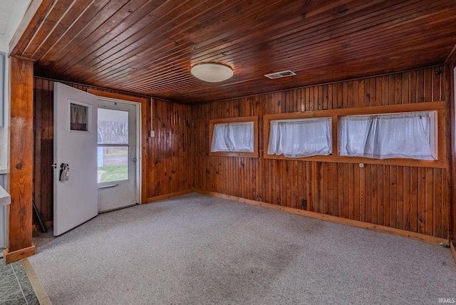 empty room featuring light carpet, wooden ceiling, and wood walls