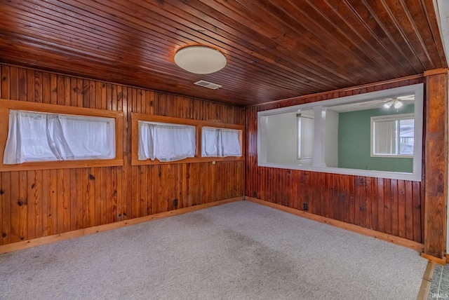 carpeted spare room featuring wooden ceiling and wood walls