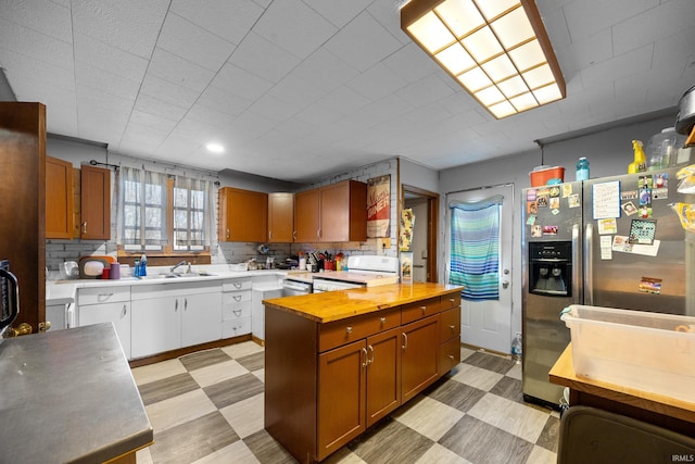 kitchen featuring wood counters, stainless steel fridge, decorative backsplash, white range oven, and sink