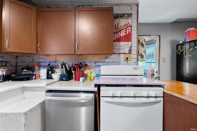 kitchen featuring backsplash, black refrigerator, stainless steel dishwasher, and white range