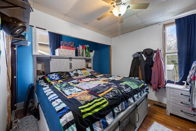 bedroom featuring a drop ceiling, hardwood / wood-style flooring, and ceiling fan