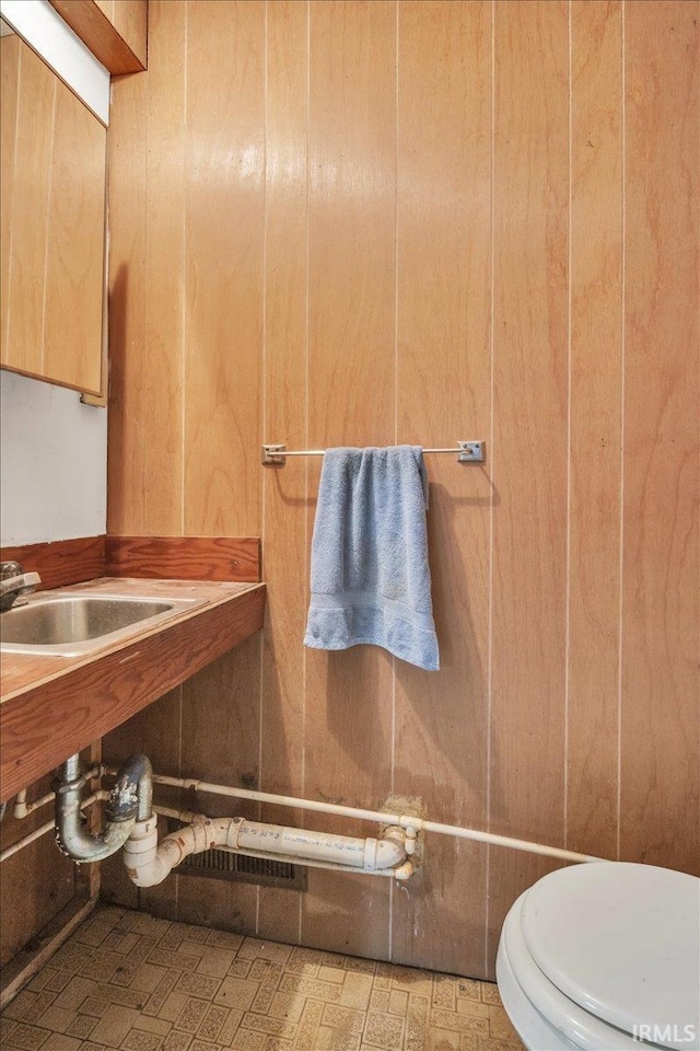 bathroom with wood walls and toilet