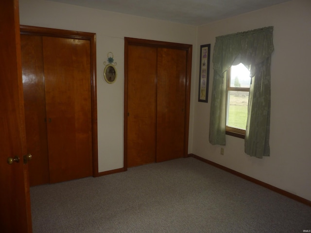 unfurnished bedroom featuring two closets and light colored carpet