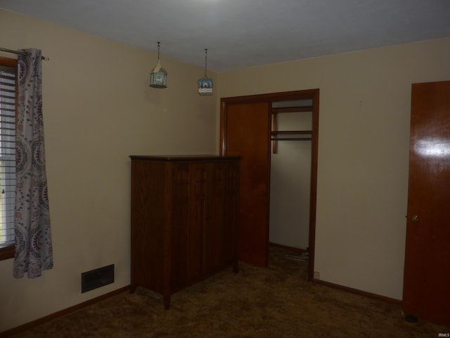 unfurnished bedroom with a closet and dark colored carpet