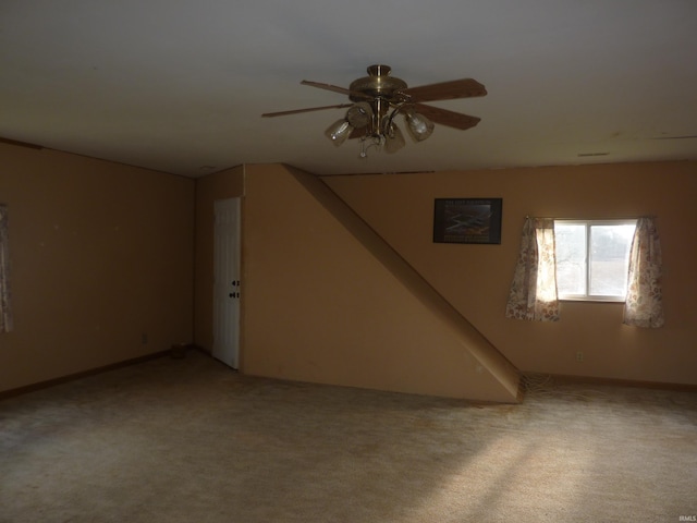 basement with ceiling fan and light colored carpet