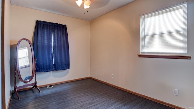 empty room with dark hardwood / wood-style floors, a healthy amount of sunlight, and ceiling fan