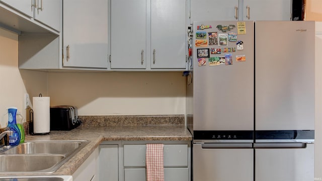 kitchen with stainless steel fridge, sink, and white cabinets