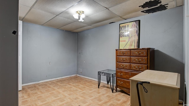 interior space with light parquet flooring and a drop ceiling