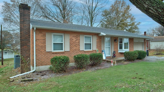 view of front of home featuring central AC, a front yard, and a garage