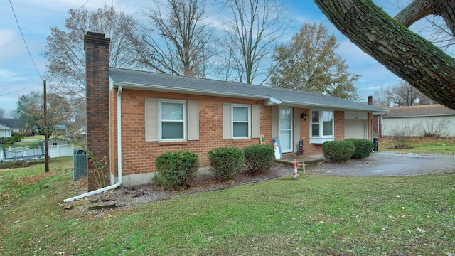 ranch-style home featuring a front yard, a garage, and central AC unit