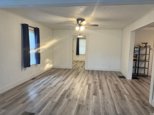 spare room with ceiling fan, light hardwood / wood-style floors, a textured ceiling, and ornamental molding