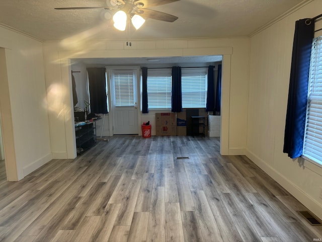 unfurnished living room featuring a textured ceiling, ceiling fan, light hardwood / wood-style floors, and crown molding