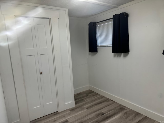 unfurnished bedroom with a textured ceiling, light hardwood / wood-style floors, and a closet