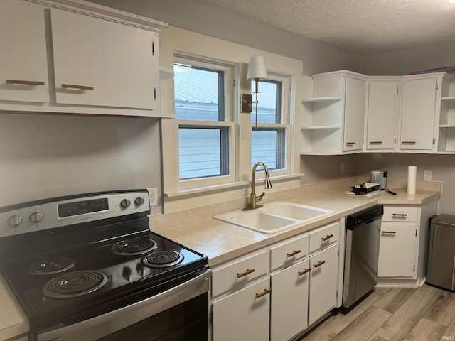 kitchen with sink, white cabinets, light hardwood / wood-style flooring, and appliances with stainless steel finishes