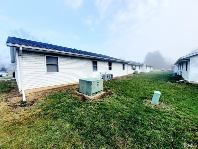 view of side of property with a yard and central AC