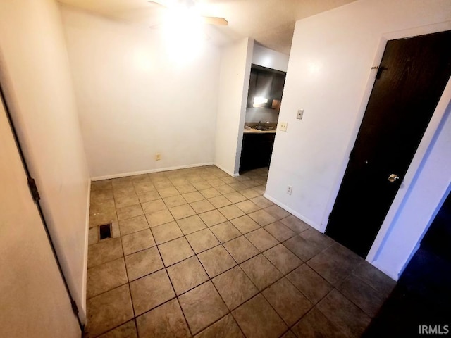 tiled empty room featuring ceiling fan