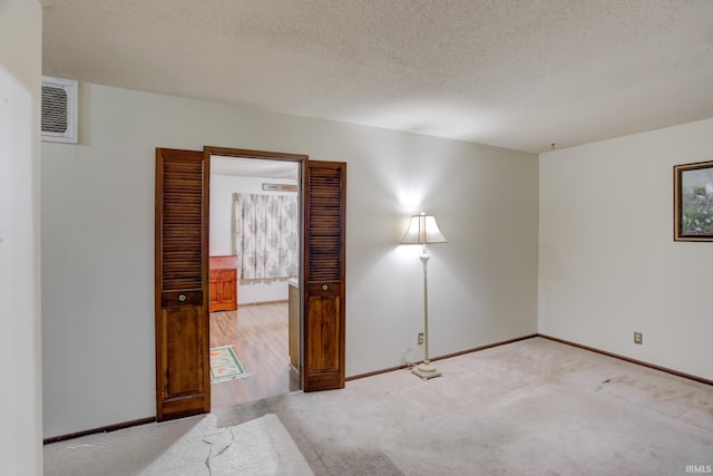 spare room featuring light carpet and a textured ceiling