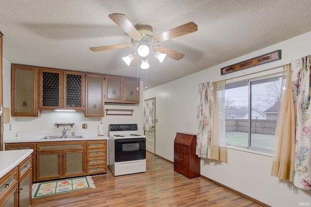 kitchen with a textured ceiling, sink, light hardwood / wood-style floors, and electric stove