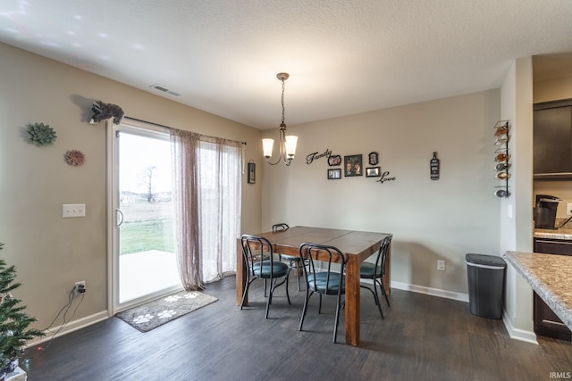 dining area featuring dark wood-type flooring, a textured ceiling, and an inviting chandelier