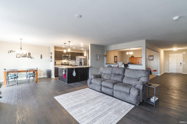 living room featuring a notable chandelier, dark hardwood / wood-style flooring, and a textured ceiling