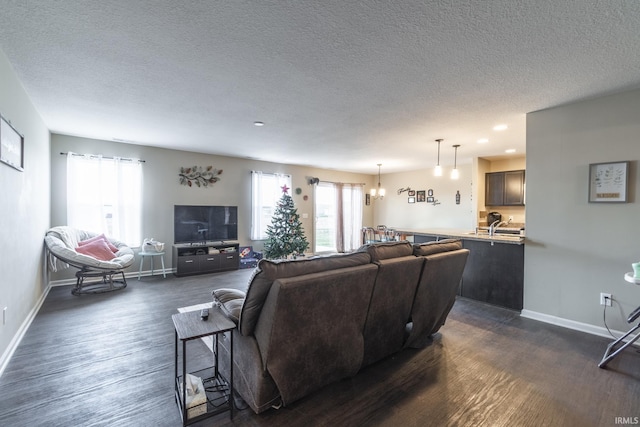 living room featuring a textured ceiling, dark hardwood / wood-style floors, an inviting chandelier, and sink