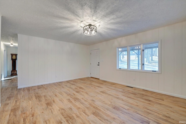 spare room with light hardwood / wood-style floors and a textured ceiling