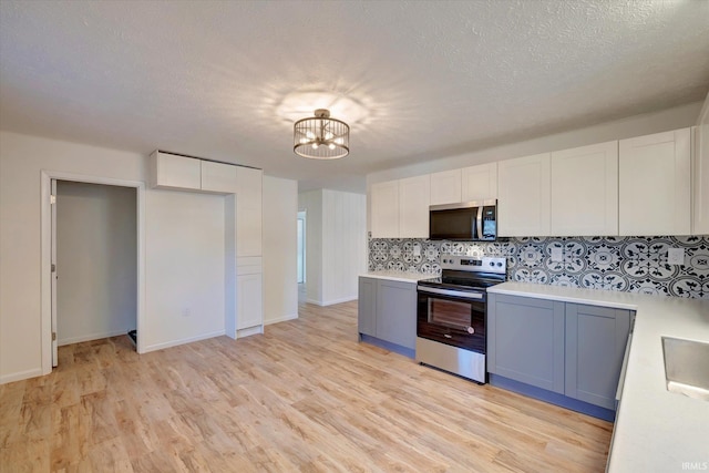 kitchen with white cabinets, light hardwood / wood-style floors, stainless steel appliances, and tasteful backsplash