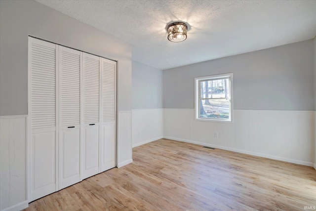 unfurnished bedroom with a closet, a textured ceiling, and light wood-type flooring