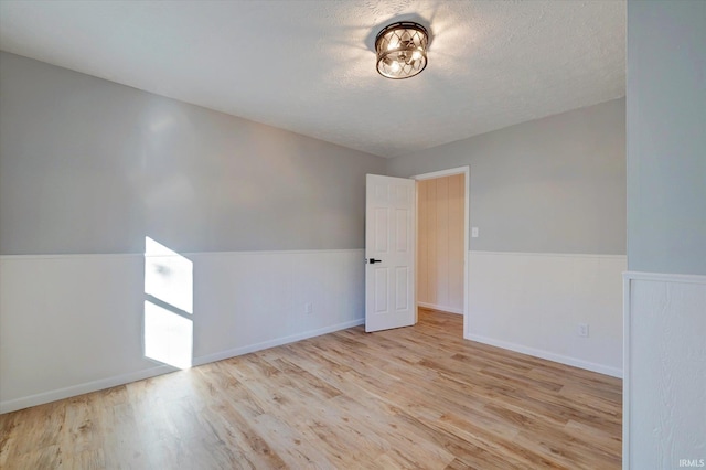 unfurnished room featuring a textured ceiling and light wood-type flooring