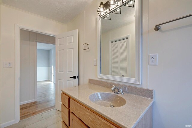 bathroom featuring hardwood / wood-style flooring, vanity, ornamental molding, and a textured ceiling