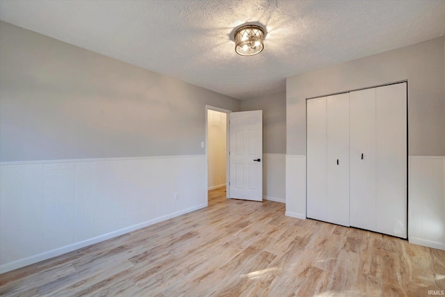 unfurnished bedroom featuring a textured ceiling, light hardwood / wood-style flooring, and a closet