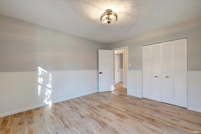 unfurnished bedroom featuring a closet, light hardwood / wood-style floors, and a textured ceiling