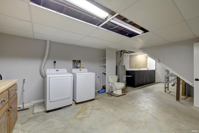 basement with washing machine and dryer, a paneled ceiling, and water heater