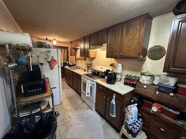 kitchen featuring dark brown cabinetry, sink, a textured ceiling, white appliances, and light tile patterned floors