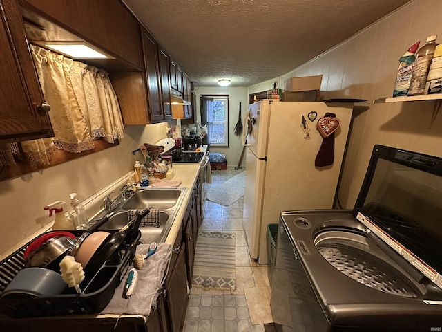 kitchen featuring white appliances, dark brown cabinets, a textured ceiling, and light tile patterned flooring