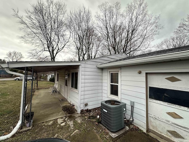 view of side of home with a carport, central air condition unit, and a yard