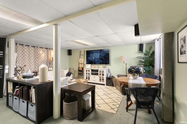 living room with a paneled ceiling and light colored carpet