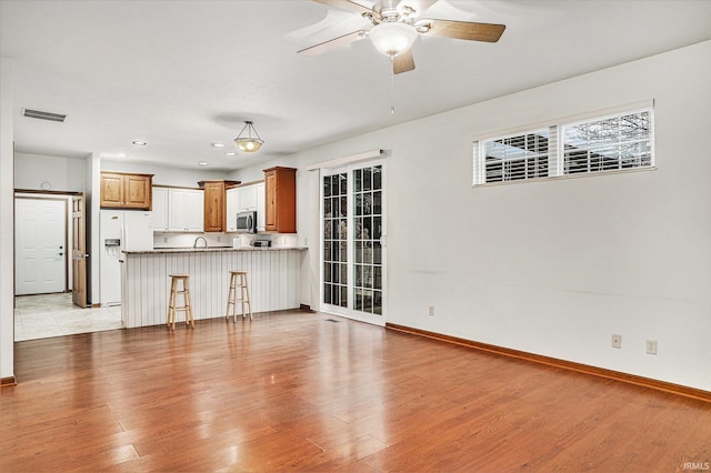 unfurnished living room featuring ceiling fan and light wood-type flooring